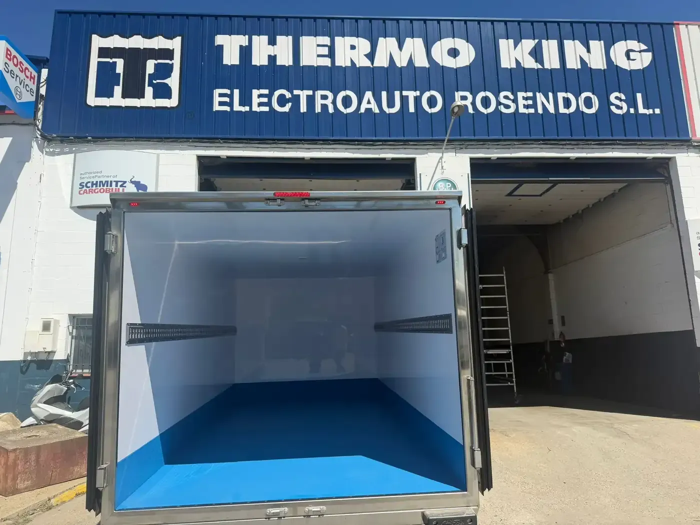 Camión de carga abierto estacionado afuera del taller Thermo King Electroauto Rosendo SL