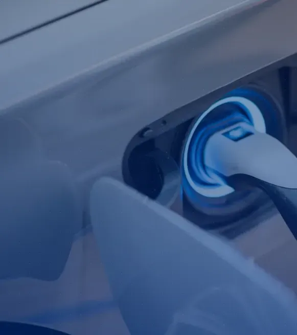 Enchufe de carga para coche eléctrico iluminado en azul conectado a un puerto de carga del vehículo.