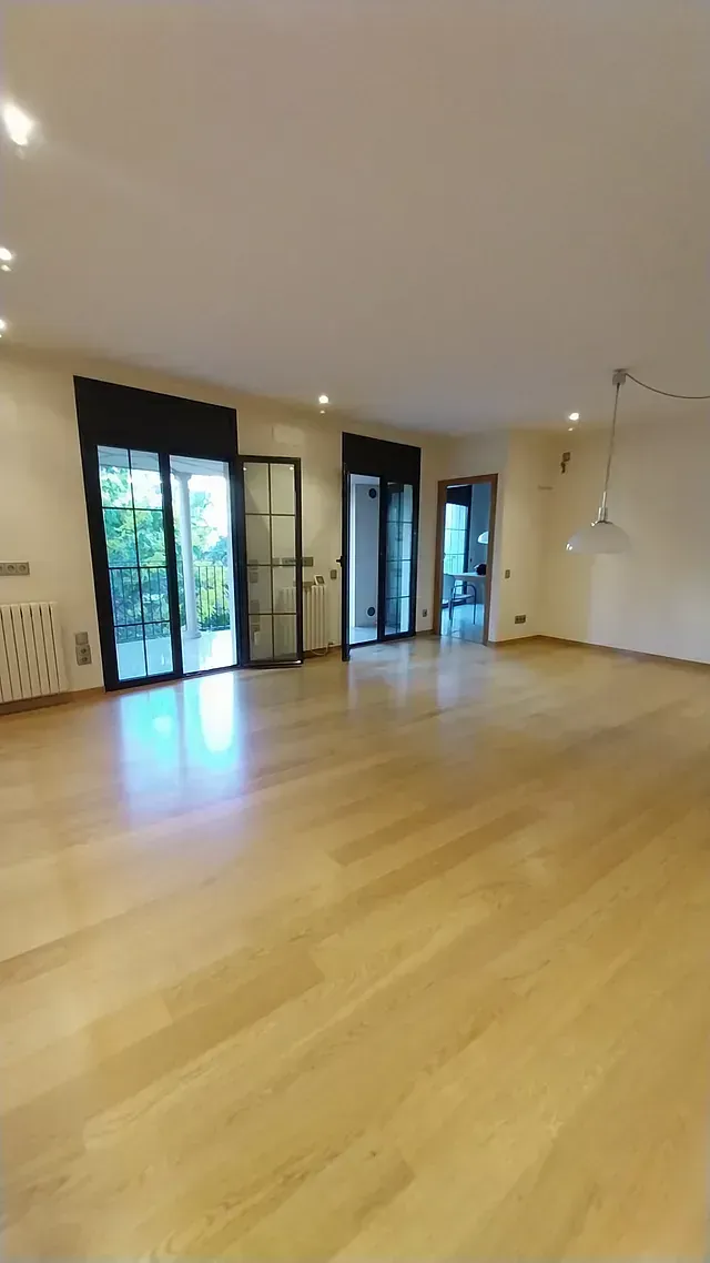 Una gran habitación vacía con pisos de madera y puertas corredizas de vidrio.