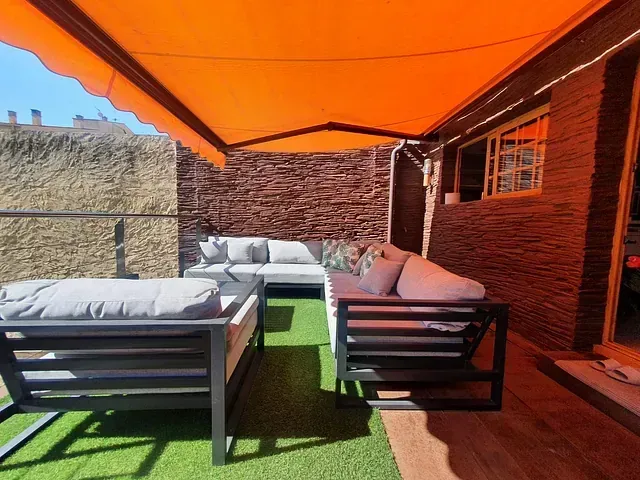 Un patio con un sofá bajo un toldo naranja.