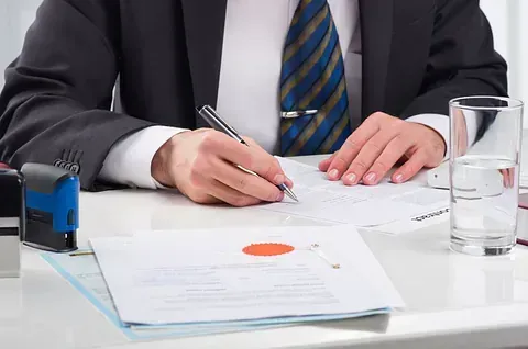 Un hombre con traje y corbata está firmando un documento.