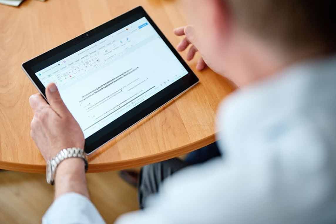 Arbeiter in Sicherheitsausrüstung blickt in der Nähe von Industrietanks nach oben.