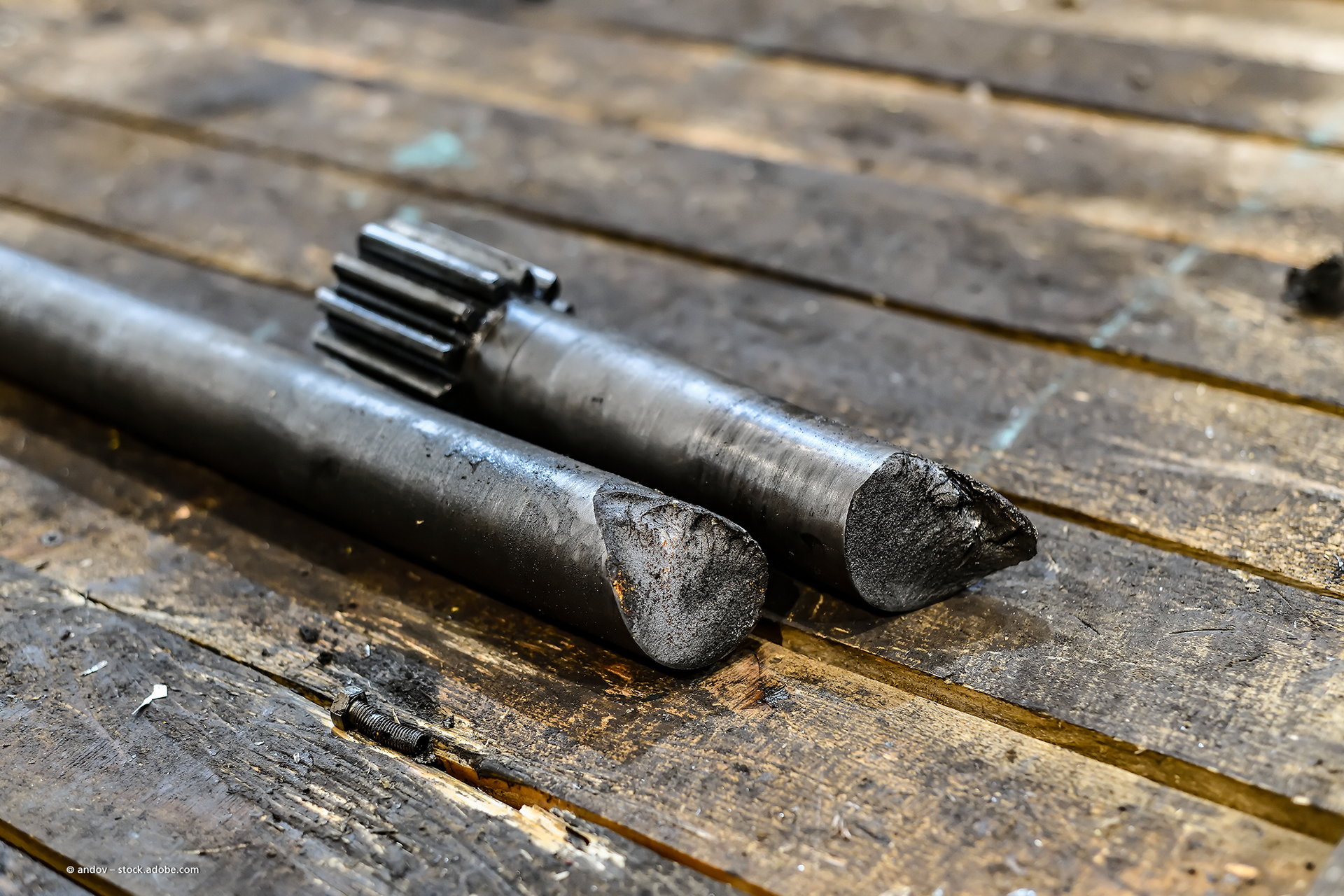 Zwei zerbrochene Metallstangen auf einer verwitterten Holzoberfläche.