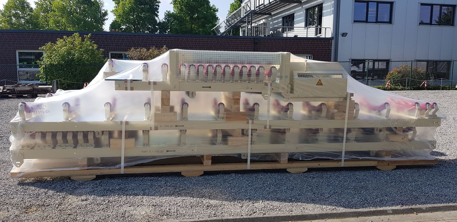 eine weiße Maschine liegt auf einem hölzernen Palette und ist mit plastik bedeckt