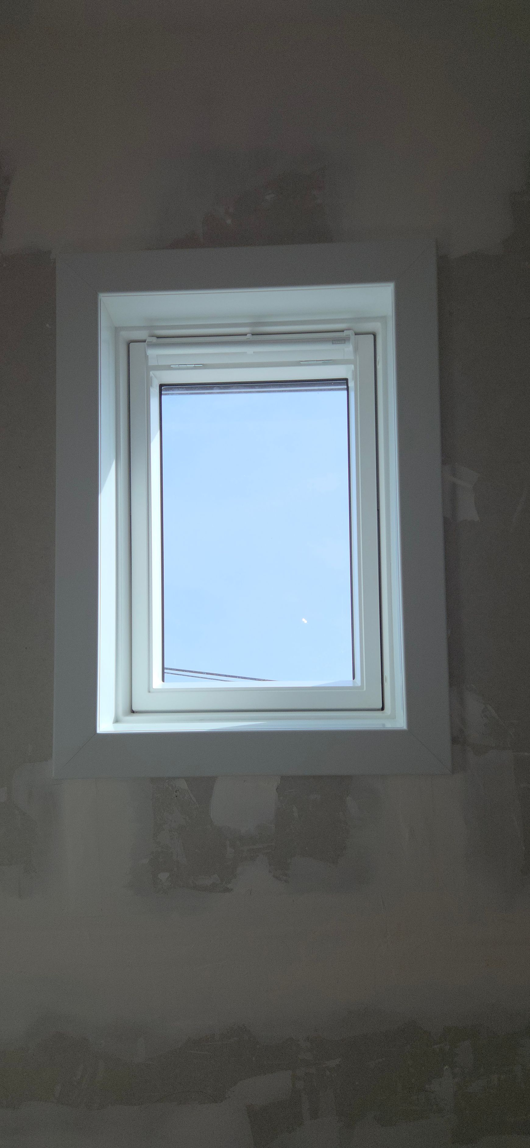 Une fenêtre de toit encastrée dans un plafond en bois, dévoilant un ciel bleu limpide.