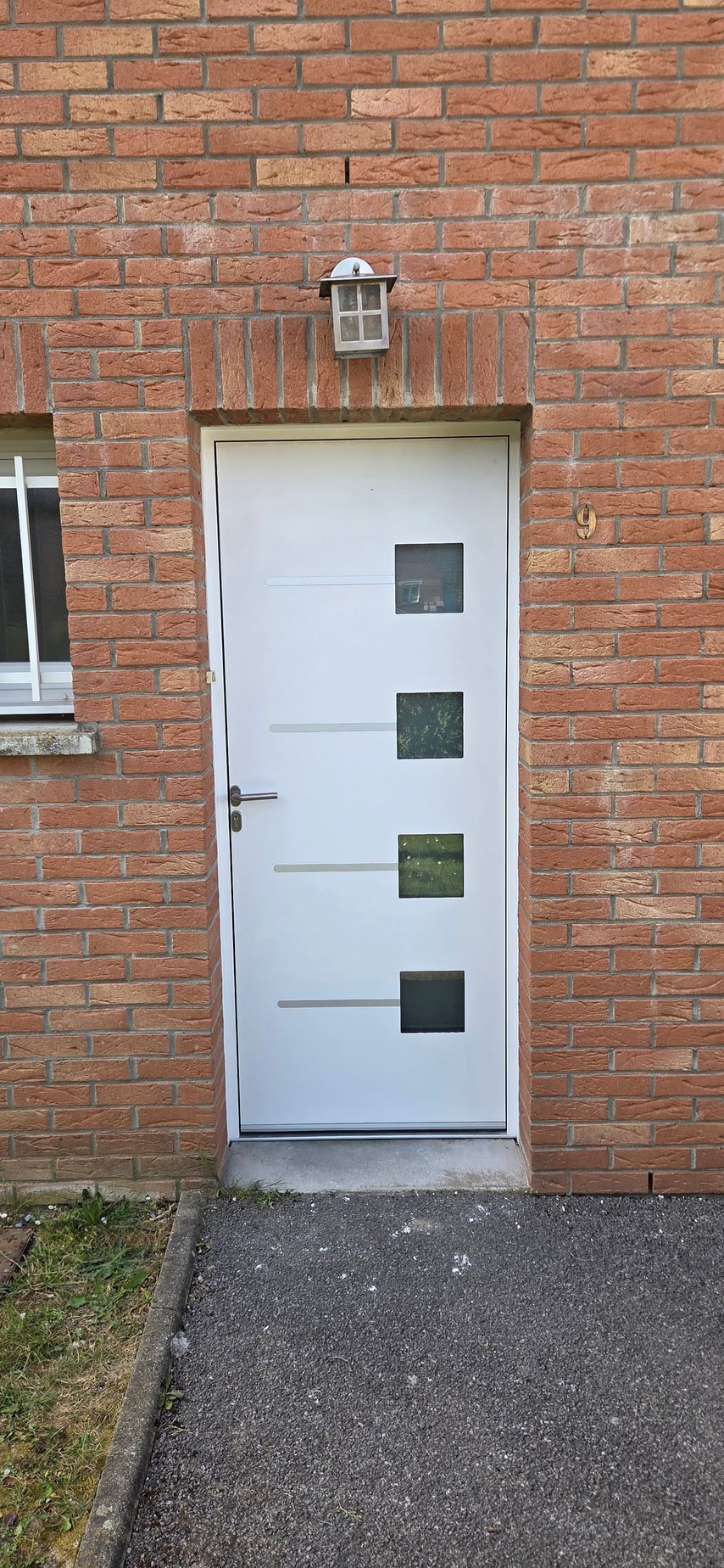 Une porte blanche entrouverte, avec un porte-clés en forme de maison accroché à la clé dans la serrure, donnant sur une pièce floue.