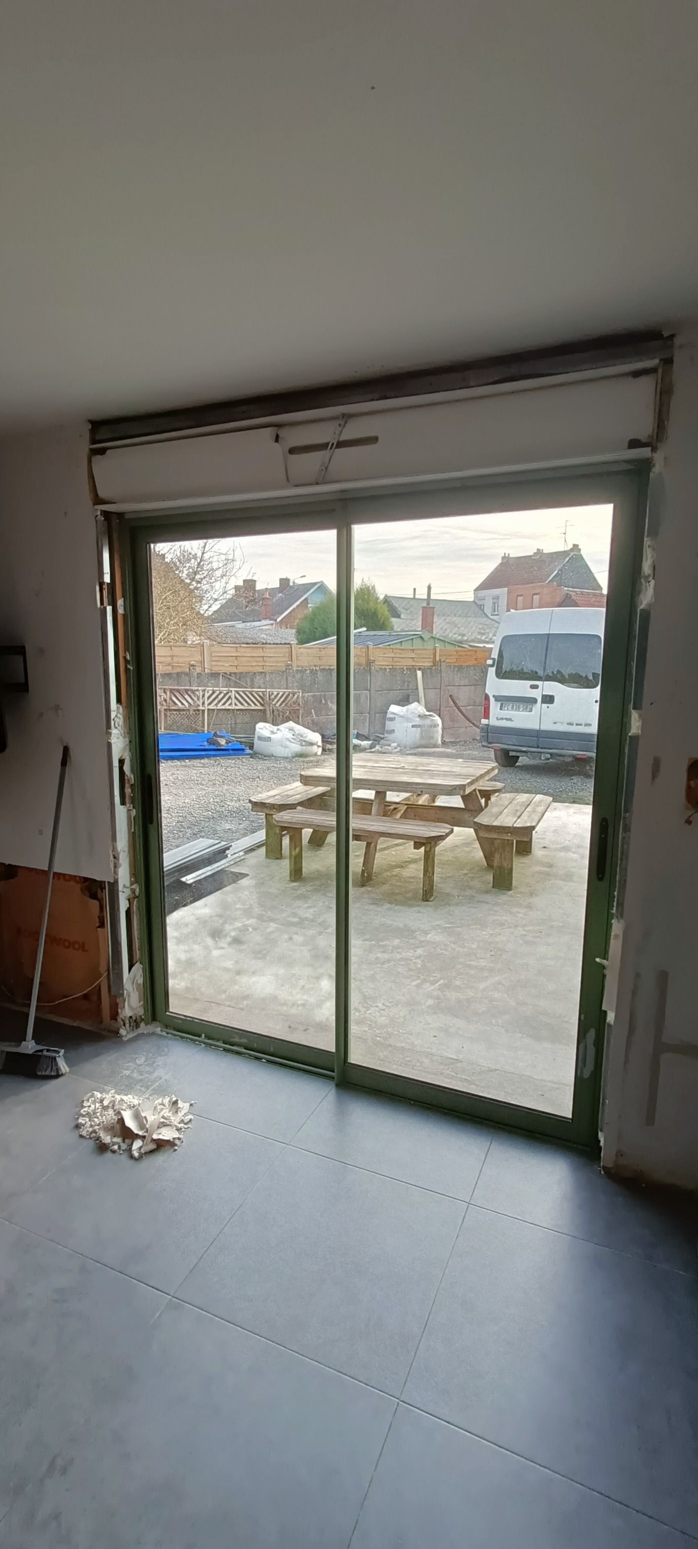 Une personne portant des bottes de travail se tient sur un escalier en bois et utilise un outil pour mesurer ou marquer le bois.