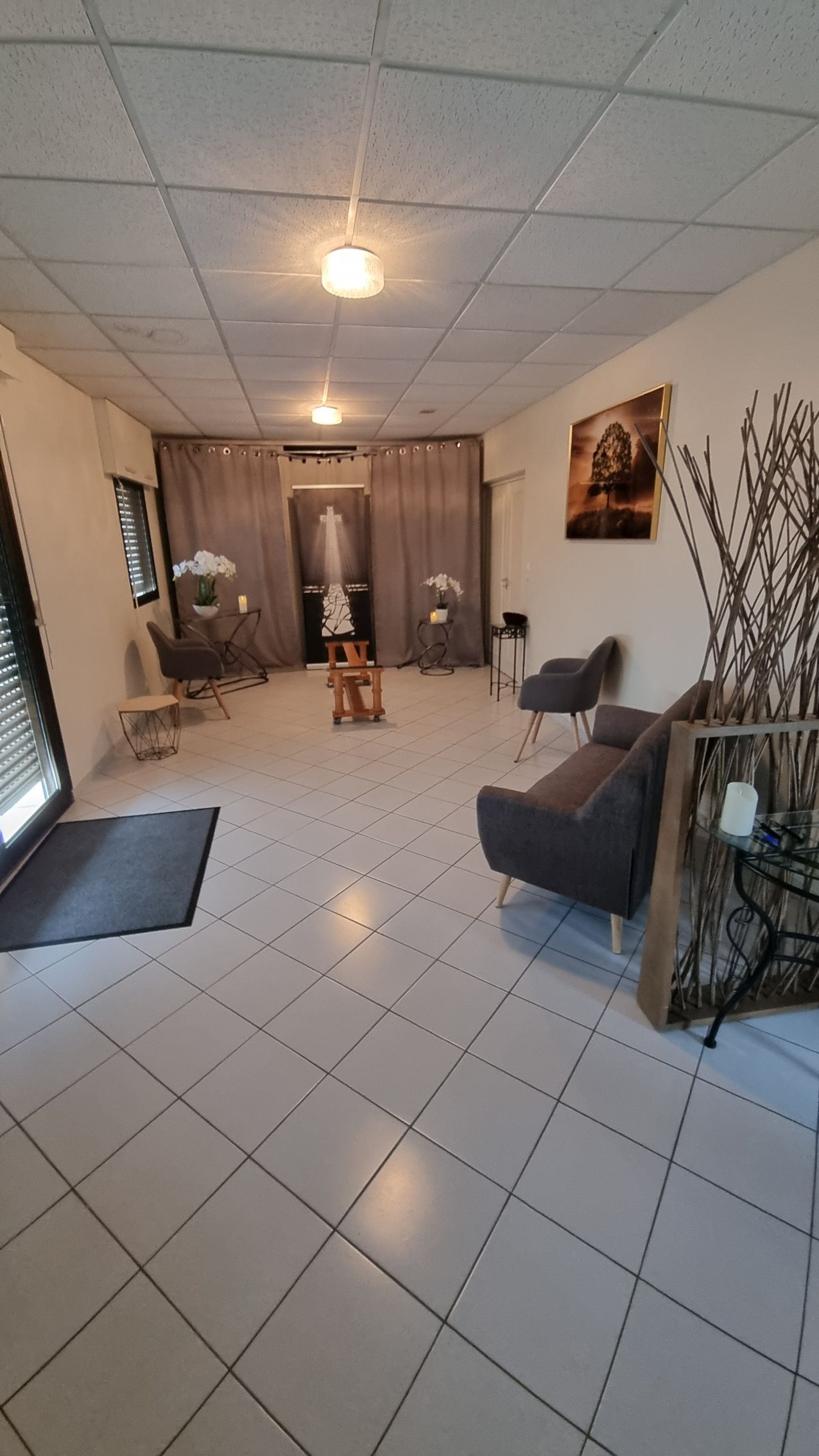 Salle d'attente avec canapé, fontaine à eau et porte donnant sur une autre pièce.