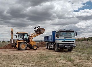 Una excavadora está cargando tierra en un camión volquete.