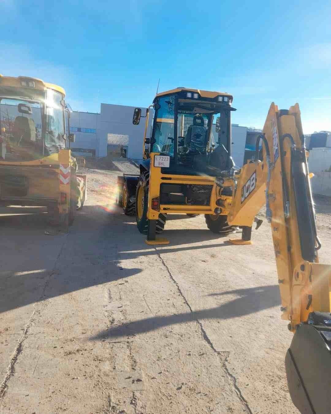 Un par de tractores amarillos están estacionados al costado de la carretera.