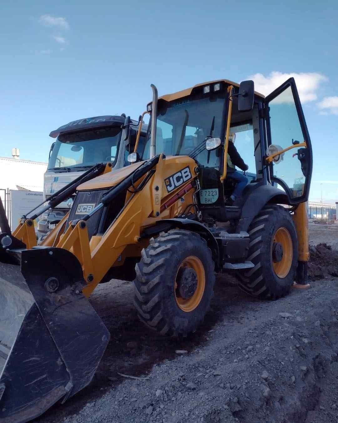 Una excavadora JCB amarilla está estacionada en un camino de tierra