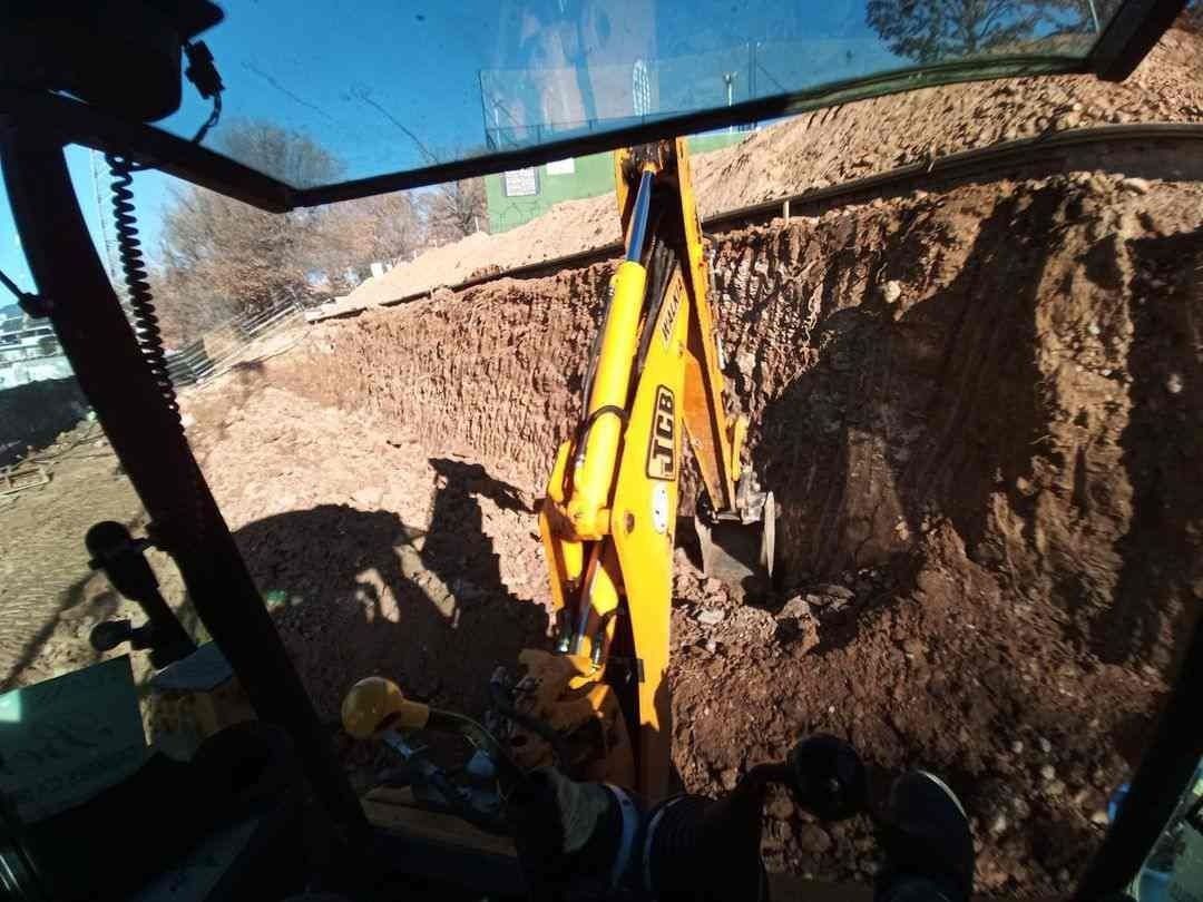 Una excavadora amarilla está cavando un hoyo en la tierra.