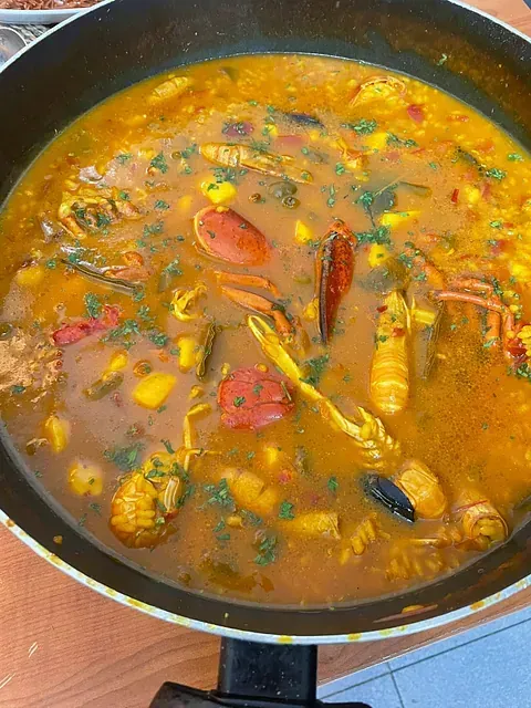 Una sartén llena de un guiso de mariscos y verduras.