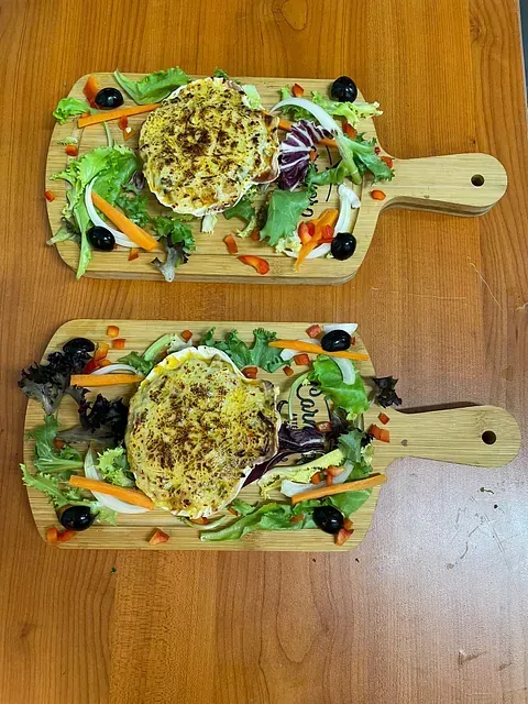 Dos tablas de cortar de madera con comida sobre ellas, sobre una mesa de madera.