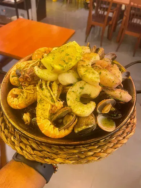 Una persona sostiene un recipiente con mariscos en su mano.
