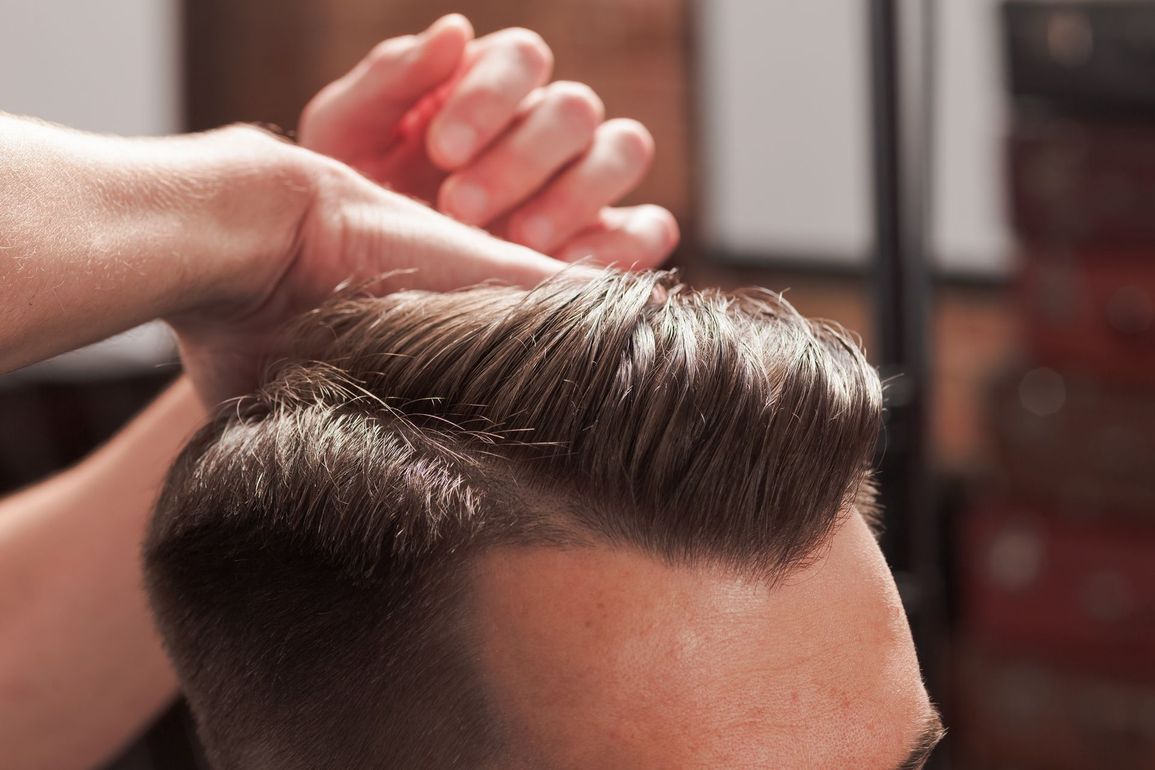Coiffeur réalisant une coiffure d'homme avec raie sur le côté