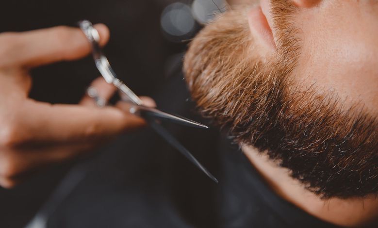 Mains tenant des ciseaux pour sculpter les poils d'une barbe
