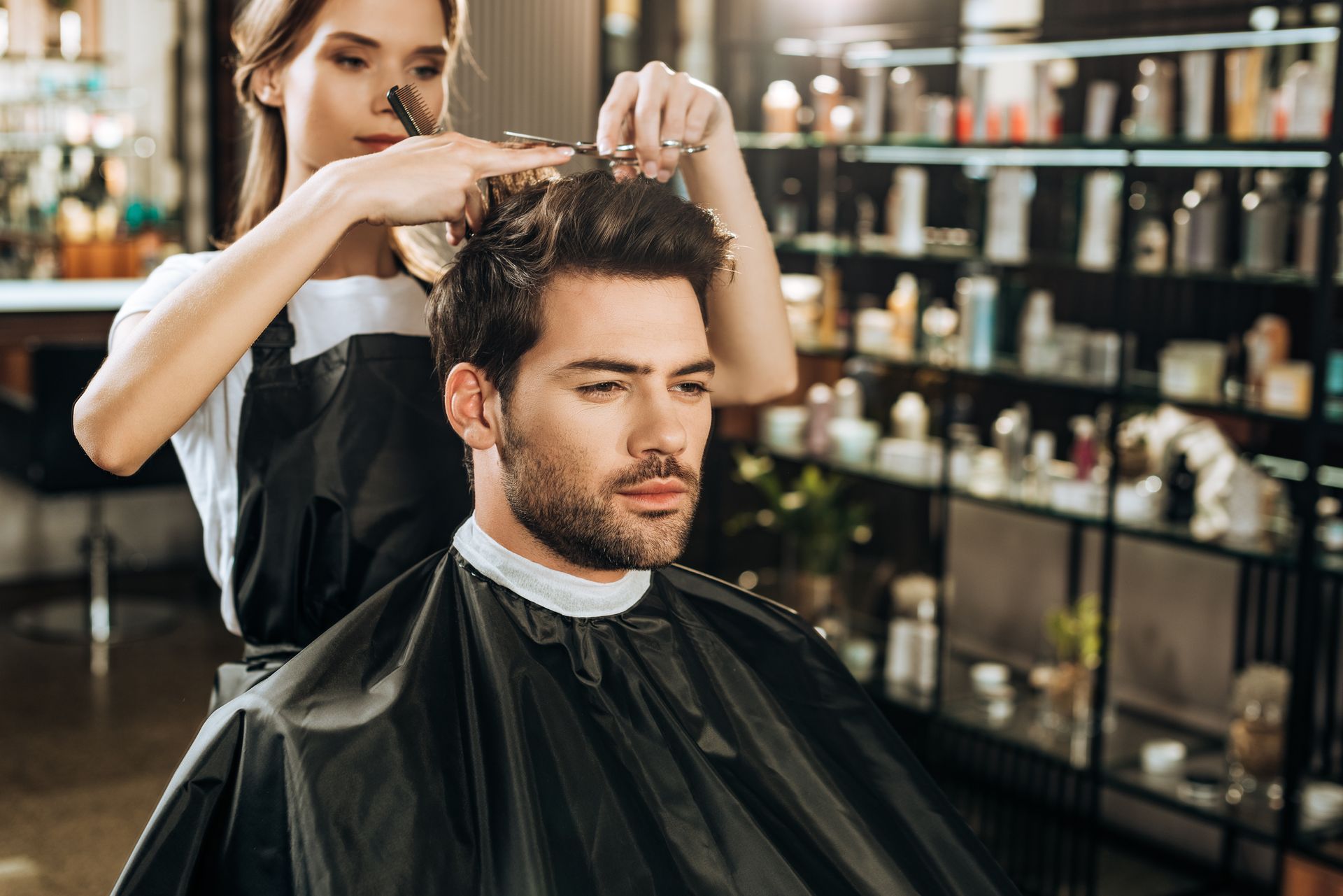 Homme en train de se faire couper les cheveux par une coiffeuse