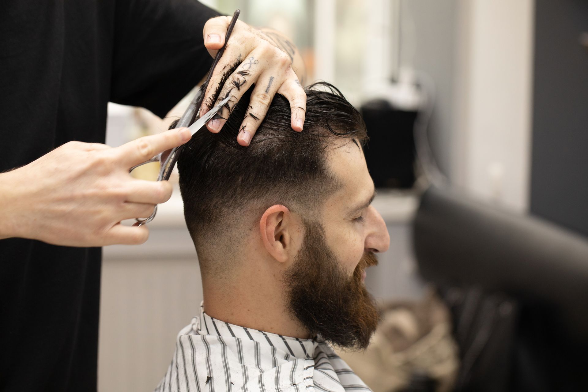 Homme barbu en train de se faire couper les cheveux aux ciseaux