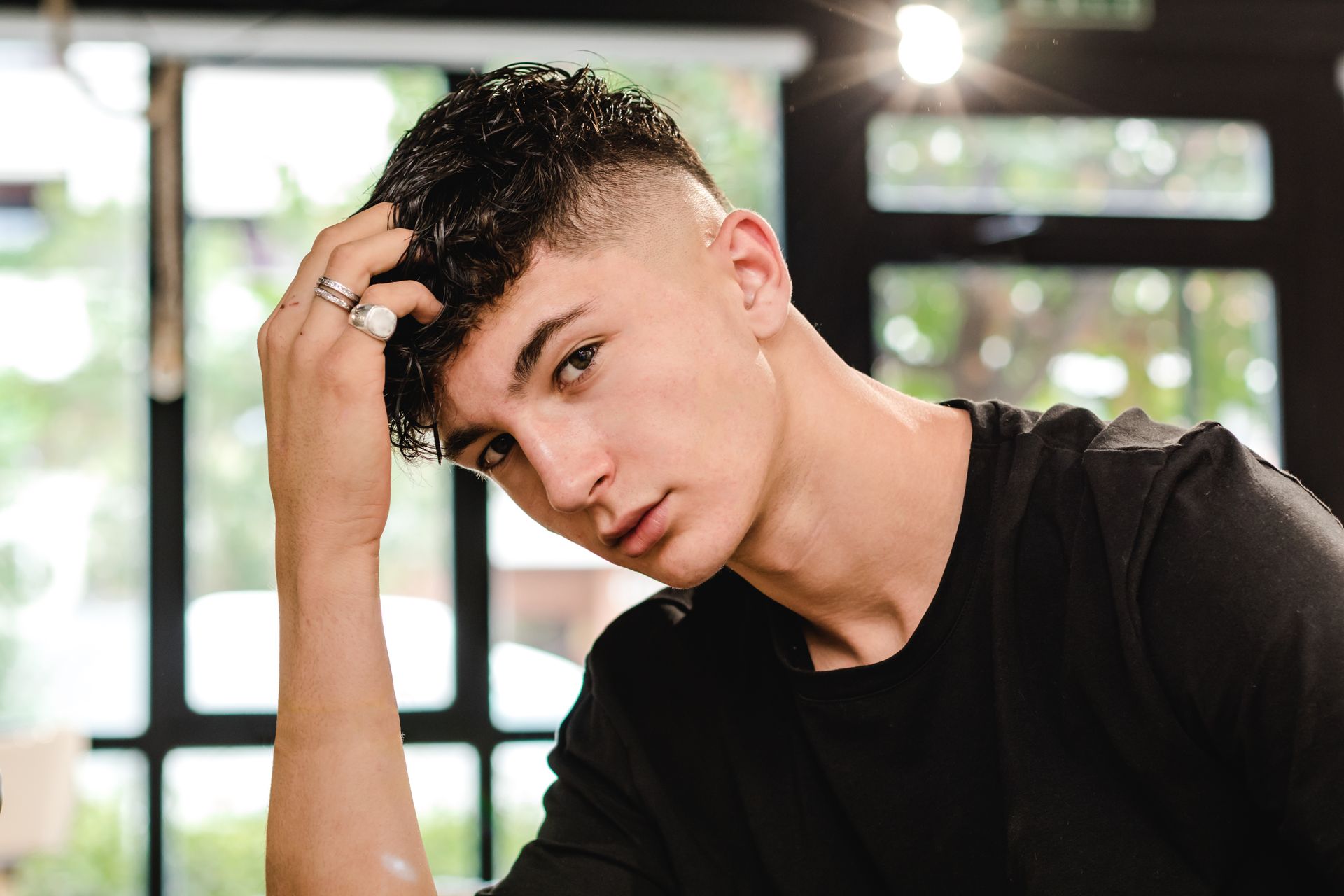 Adolescent avec une main dans les cheveux et fixant l'objectif