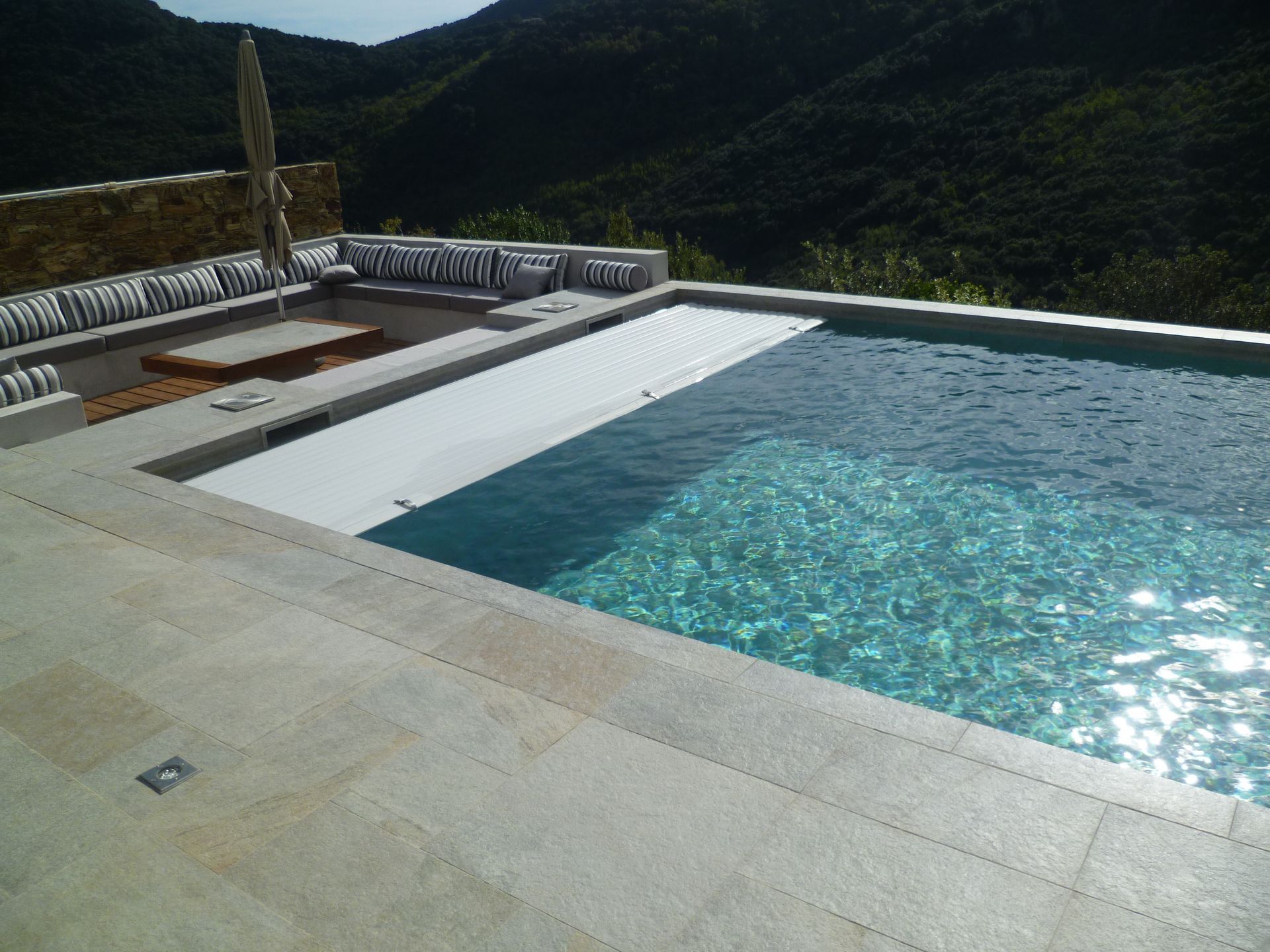Piscine en béton avec coin détente et rideau de piscine