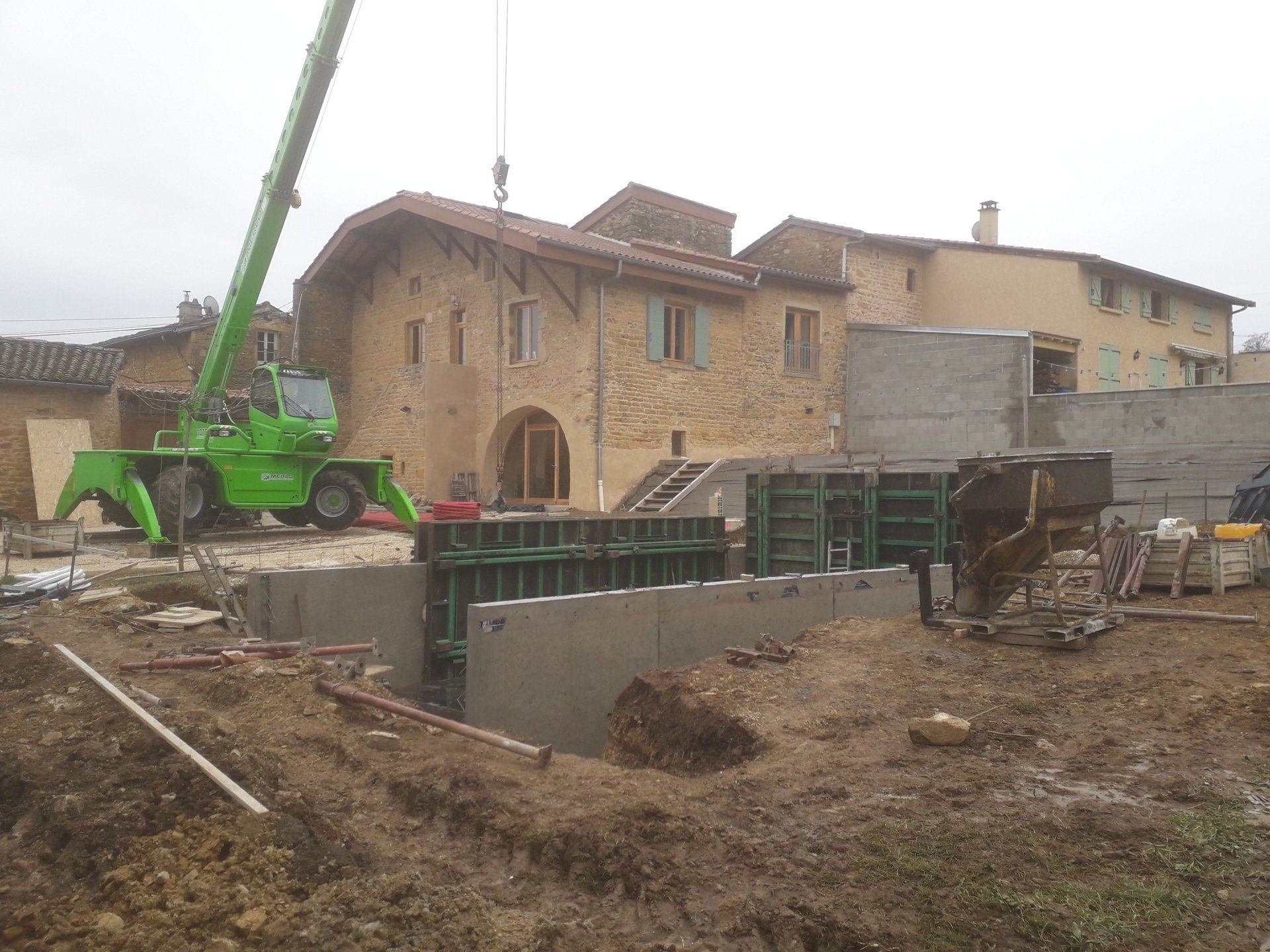 Travaux de construction d'une piscine avec maison en pierres au fond