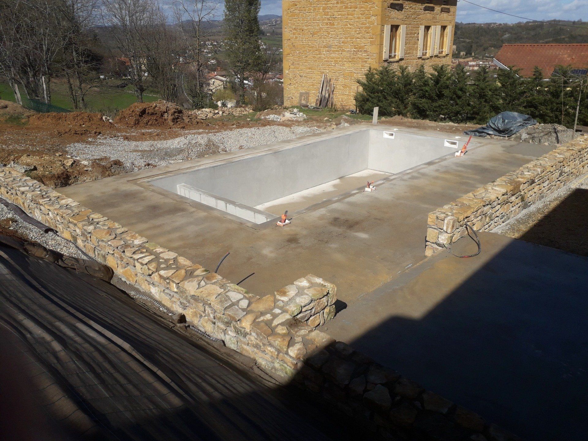 Construction d'une piscine en béton entourée de murets en pierres