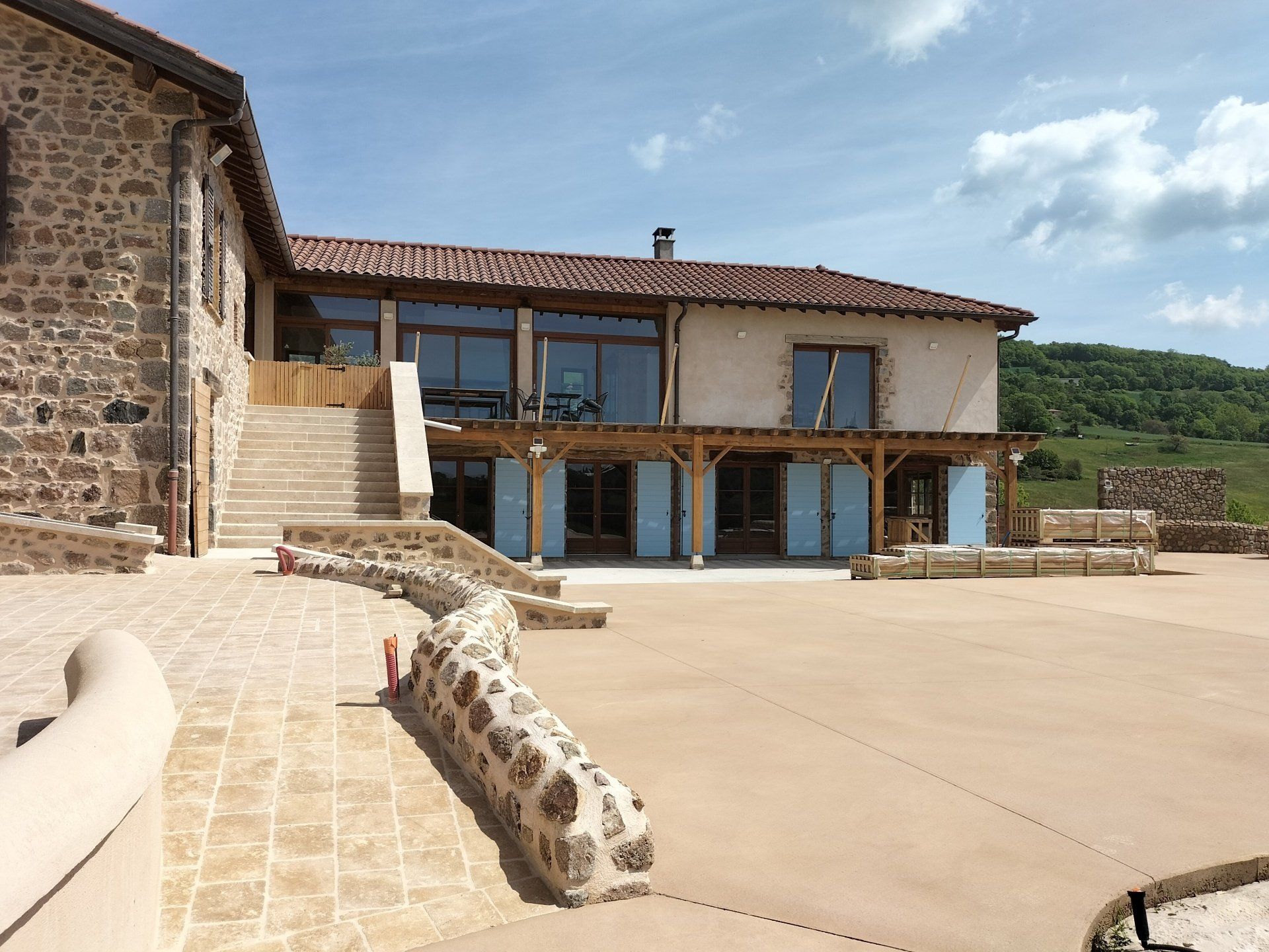 Aménagement extérieur avec murets en béton et en pierres avec maison en arrière-plan