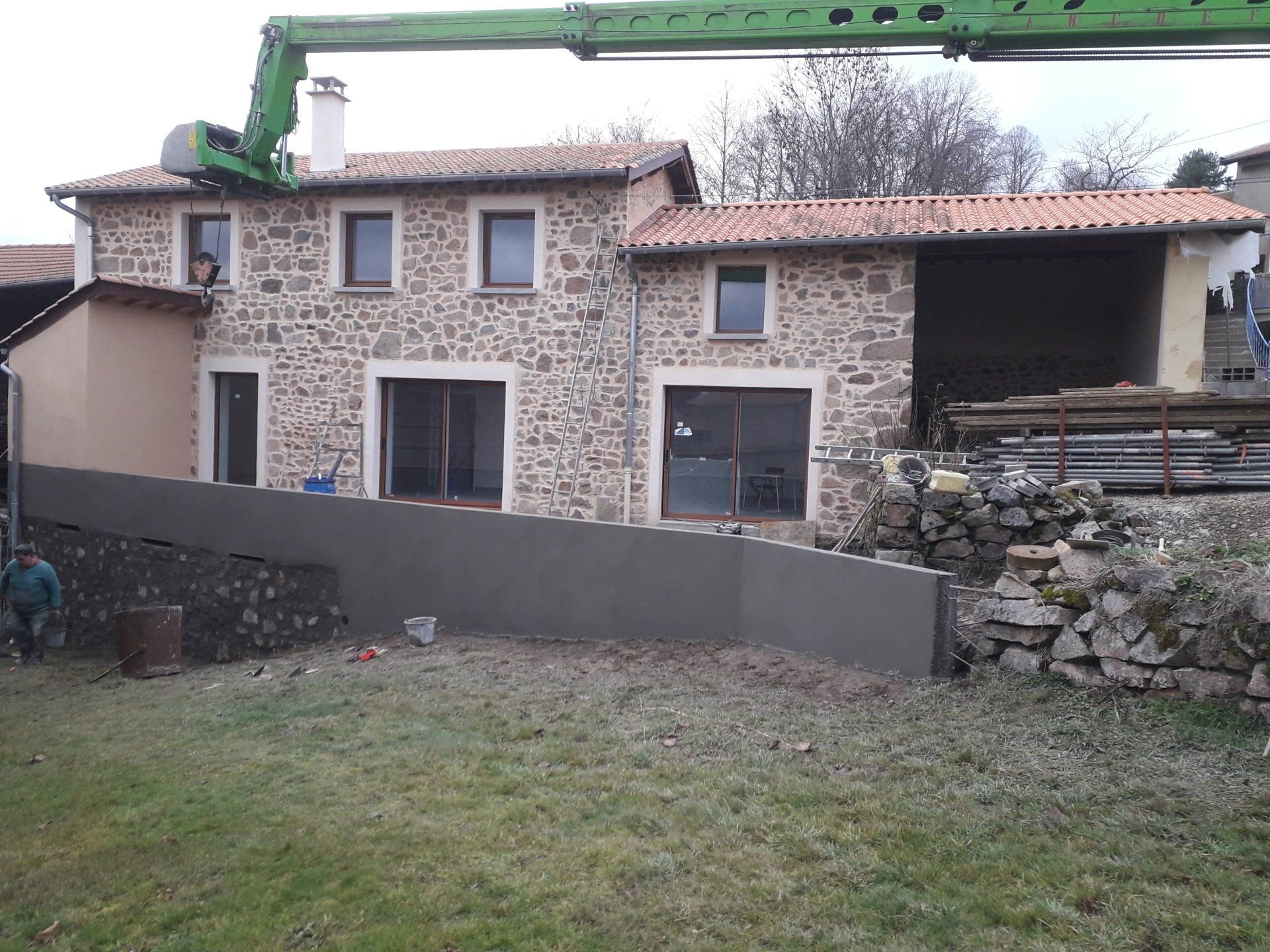 Mur en béton devant une maison en pierres