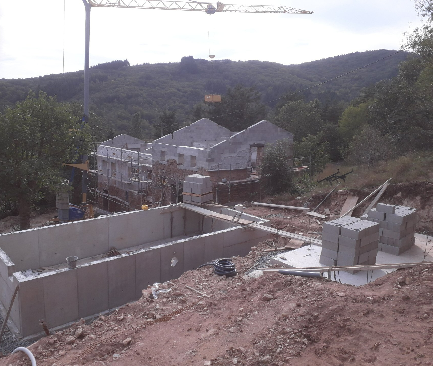 Piscine en construction et rénovation de maison en arrière plan