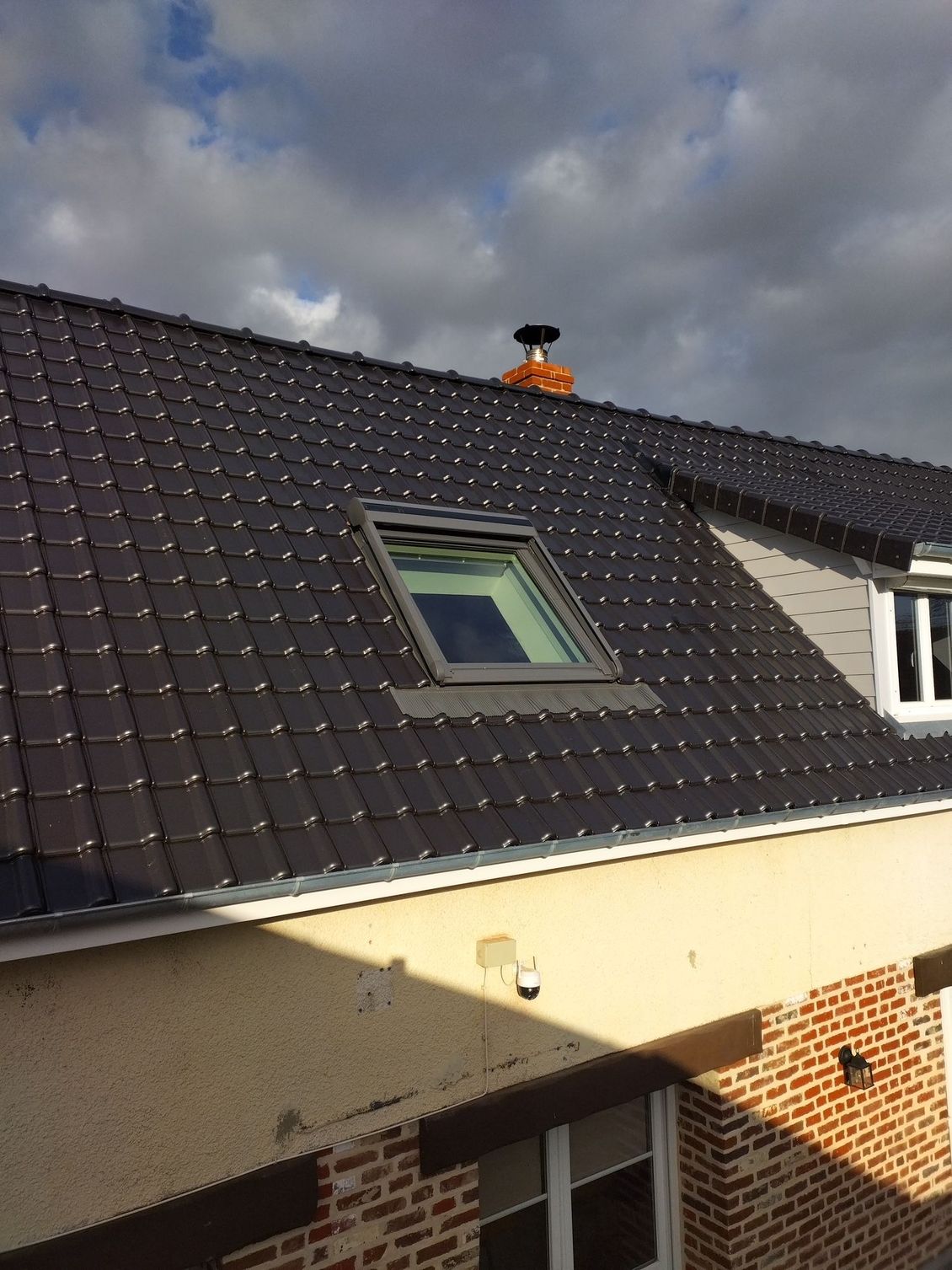 Solin de ventilation de toit autour d'une cheminée blanche sur un toit de tuiles en terre cuite orange