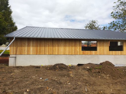 Façade de maison moderne avec lambris en lattes de bois et deux fenêtres sombres