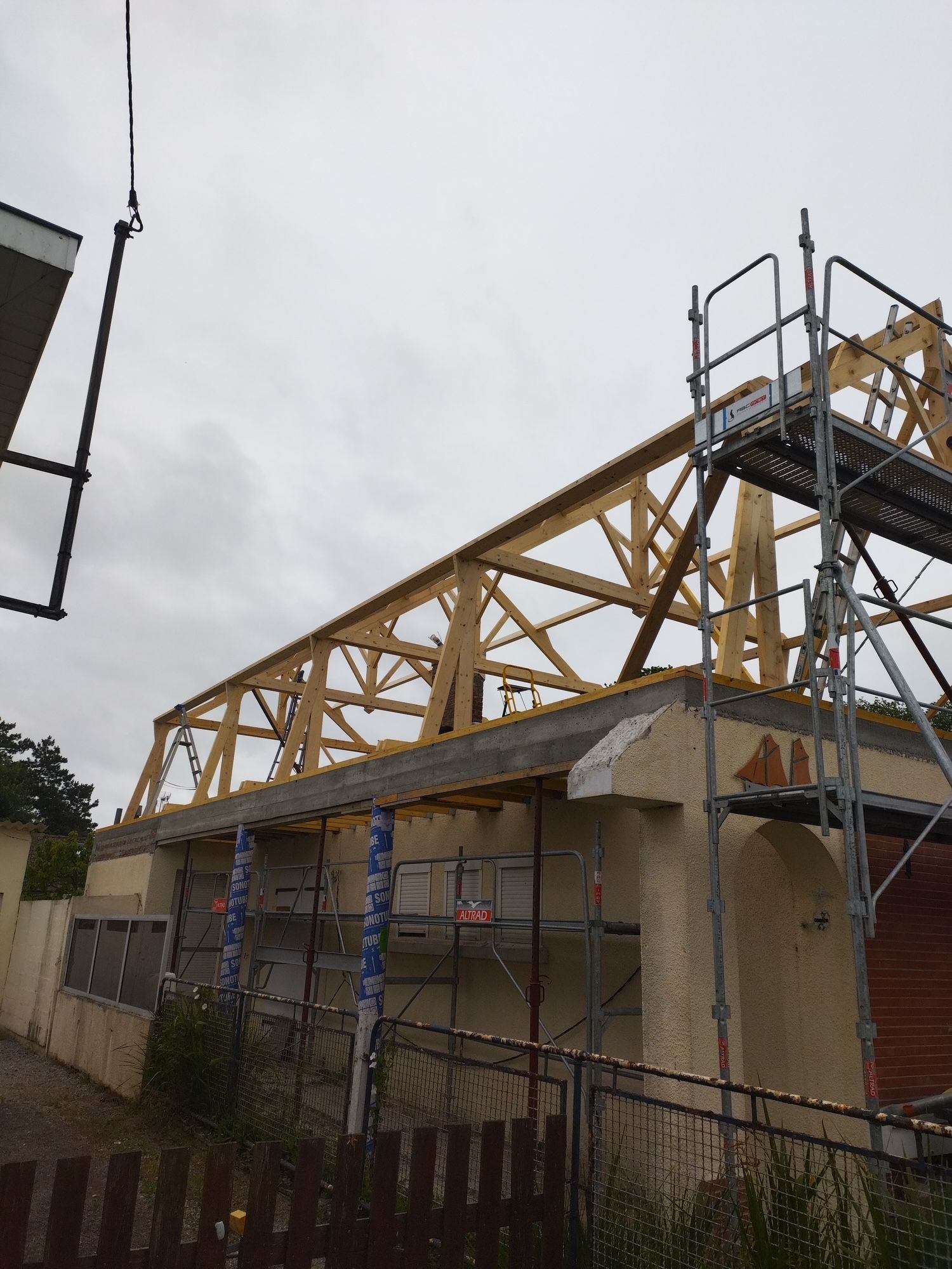 Maison partiellement construite avec une charpente en bois sur des murs en parpaings gris