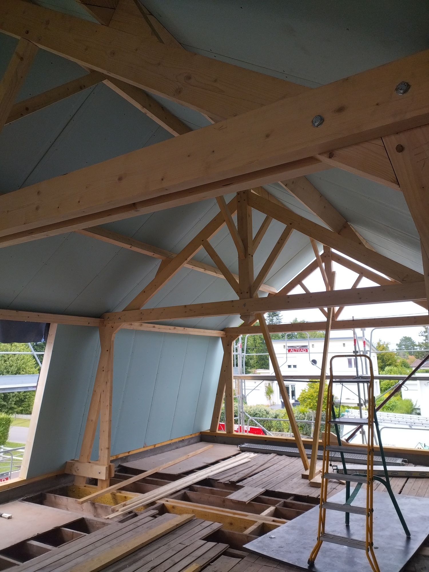 Intérieur d'un grenier à ossature en bois avec poutres inclinées et lumière du soleil projetant des ombres rayées sur le sol