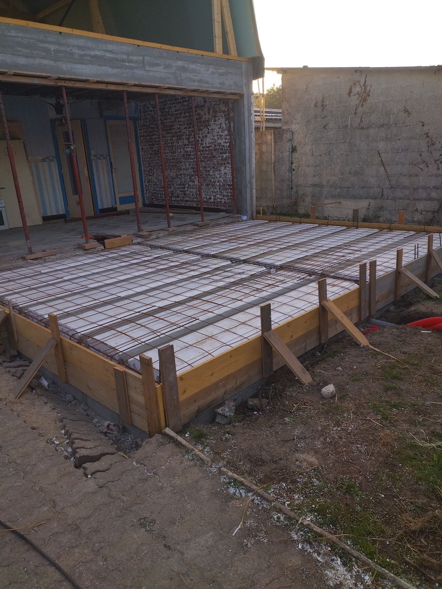 Des mains gantées lissent du béton frais à la truelle sur une surface en construction