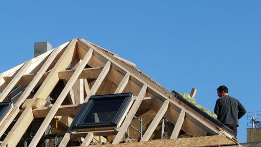 Toiture en bois se détachant sur un ciel bleu clair parsemé de nuages