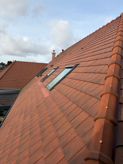 Ouvrier installant des tuiles orange sur un toit