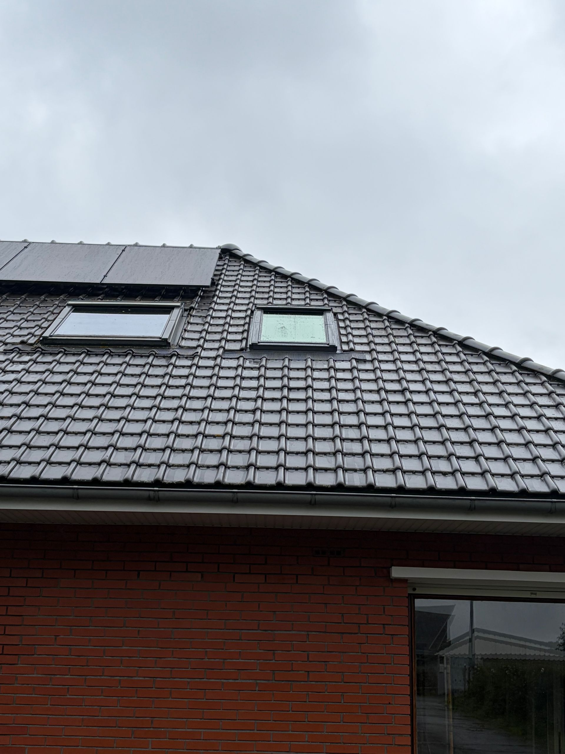 Toit en métal avec puits de lumière sous un ciel nuageux