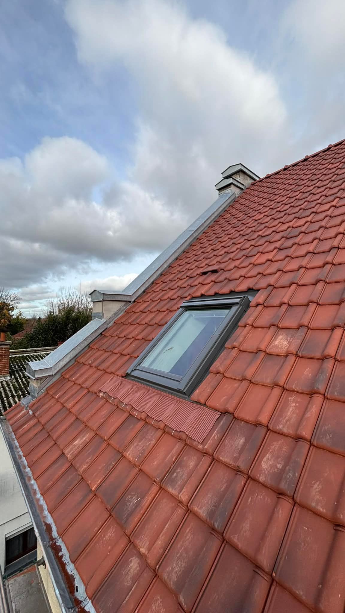Fenêtres de toit installées sur un toit de tuiles rouges sous un ciel bleu
