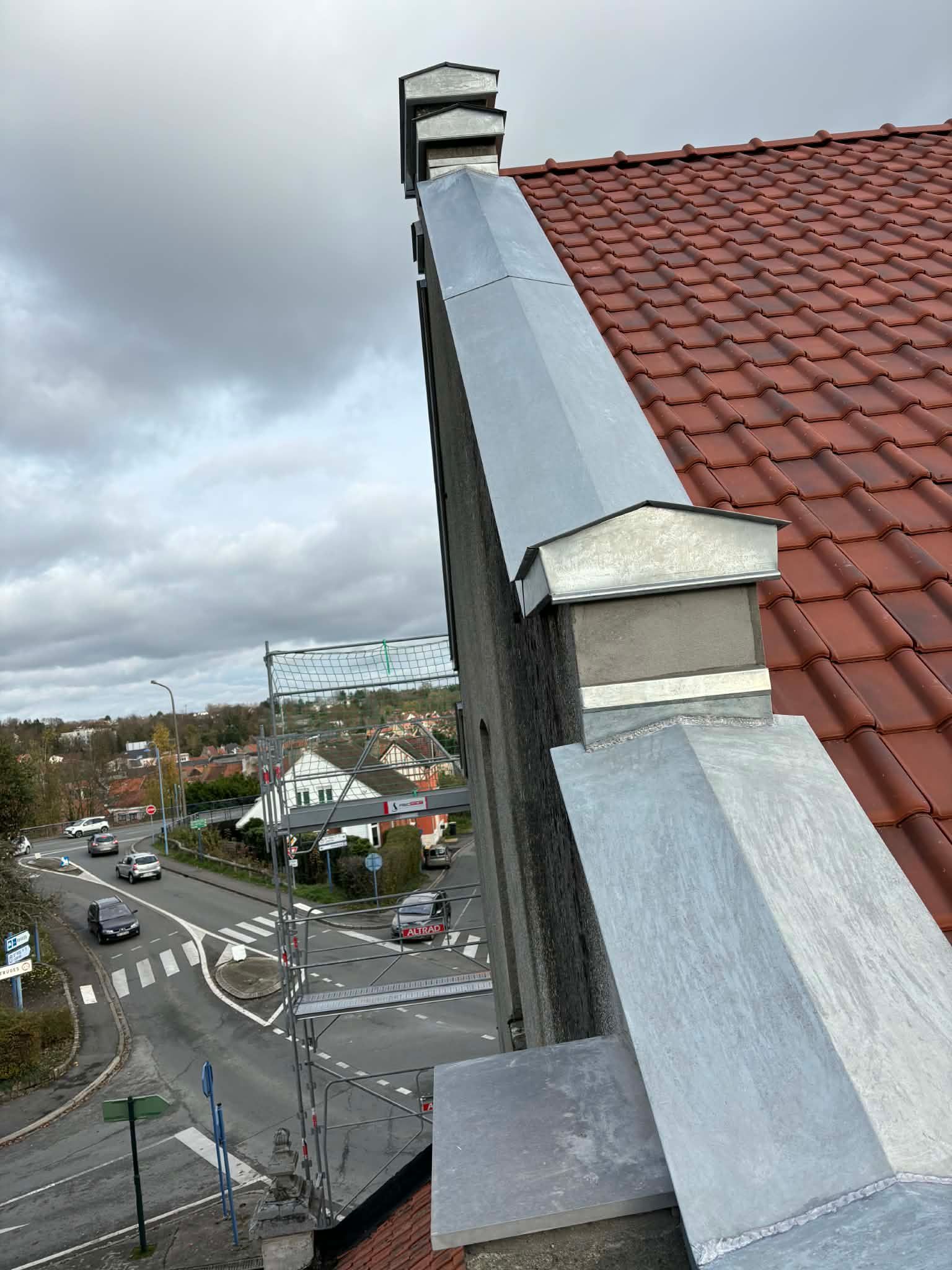 Gros plan sur le bord du toit d'un bâtiment avec un bardage gris, des garnitures blanches et des avant-toits en bois apparents.