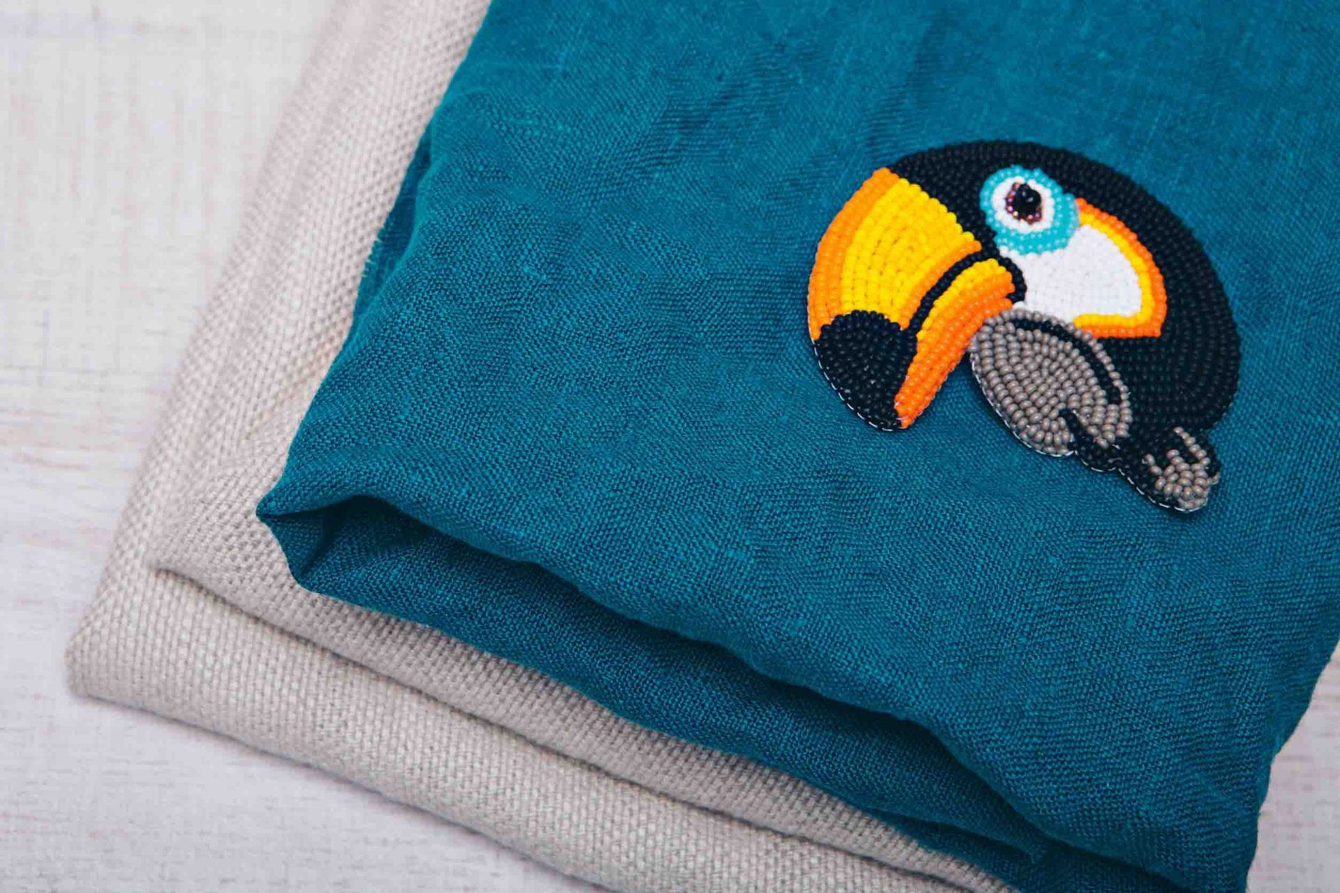 Una toalla azul con un tucán bordado en ella.