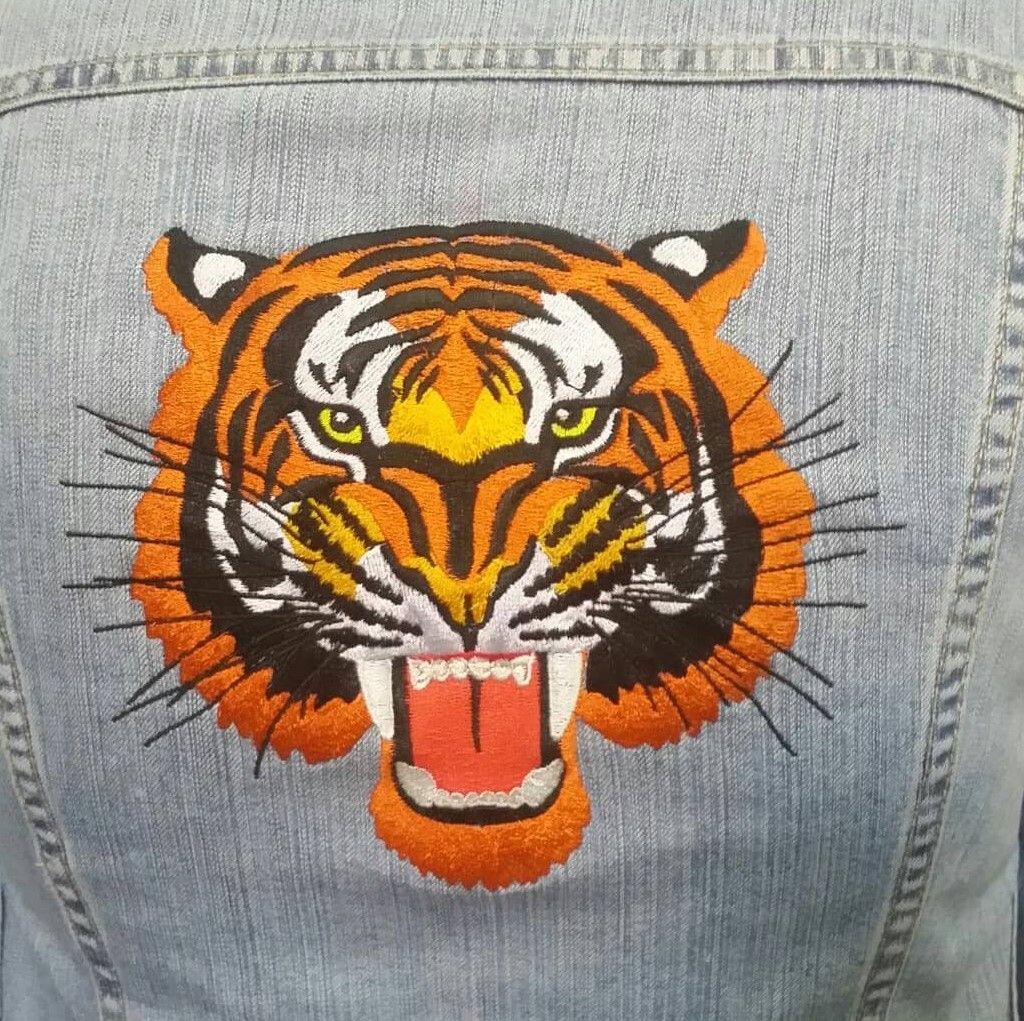Un tigre está bordado en la espalda de una chaqueta vaquera.