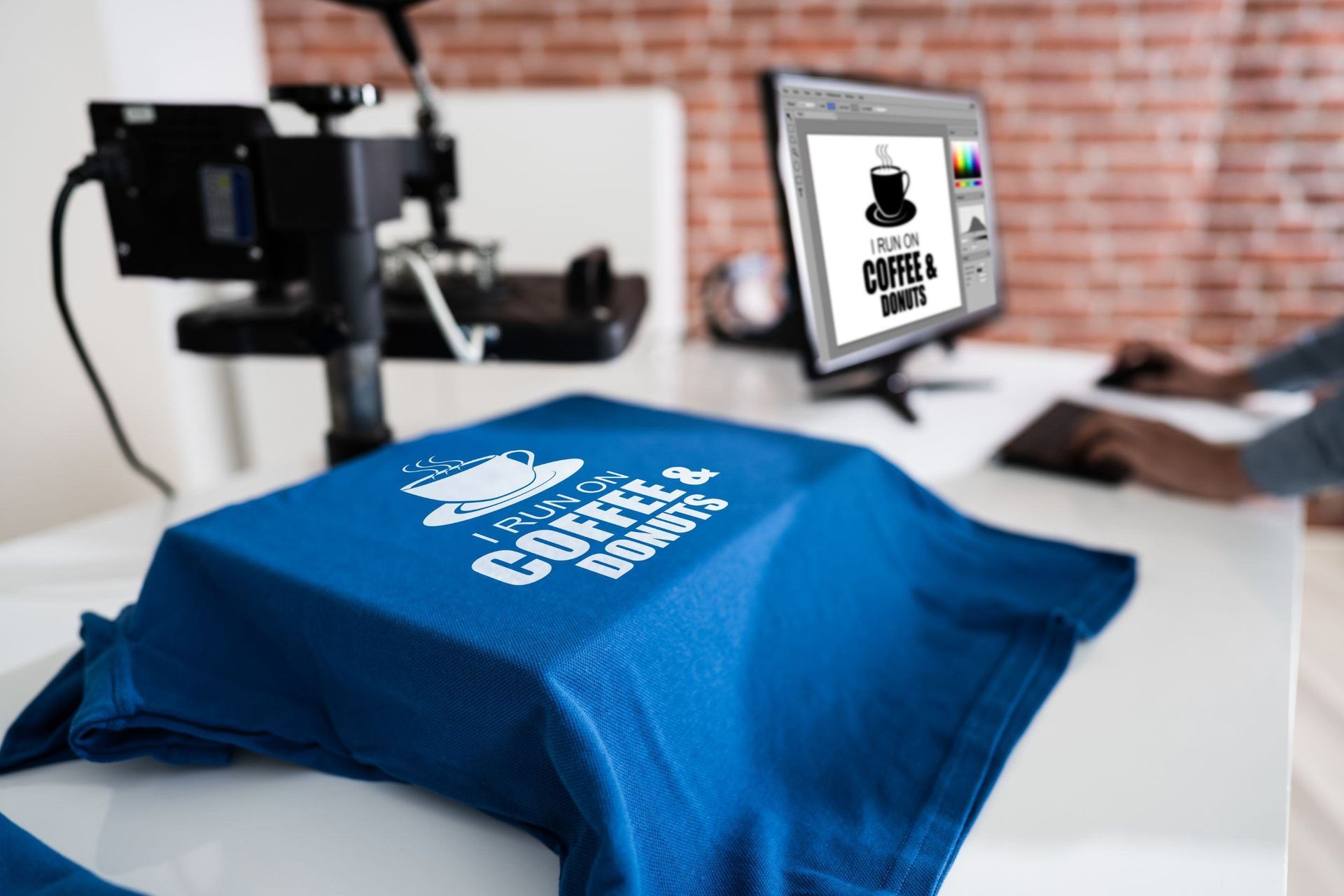 Se está imprimiendo una camiseta azul en una mesa delante de una computadora.