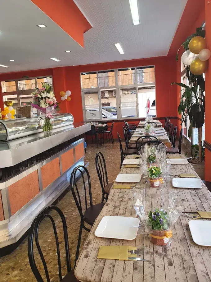 Gente cenando y charlando dentro de un bar acogedor con iluminación cálida y decoración en las paredes.