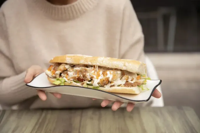 Letrero del Bar Serranía sobre un mostrador con pasteles y bandejas de comida exhibidas debajo.