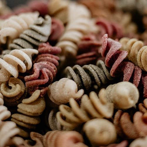 Un primer plano de una pila de pasta de diferentes colores.