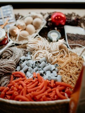 Adornos navideños variados y materiales para manualidades en una cesta, incluyendo piezas rojas, blancas y beige
