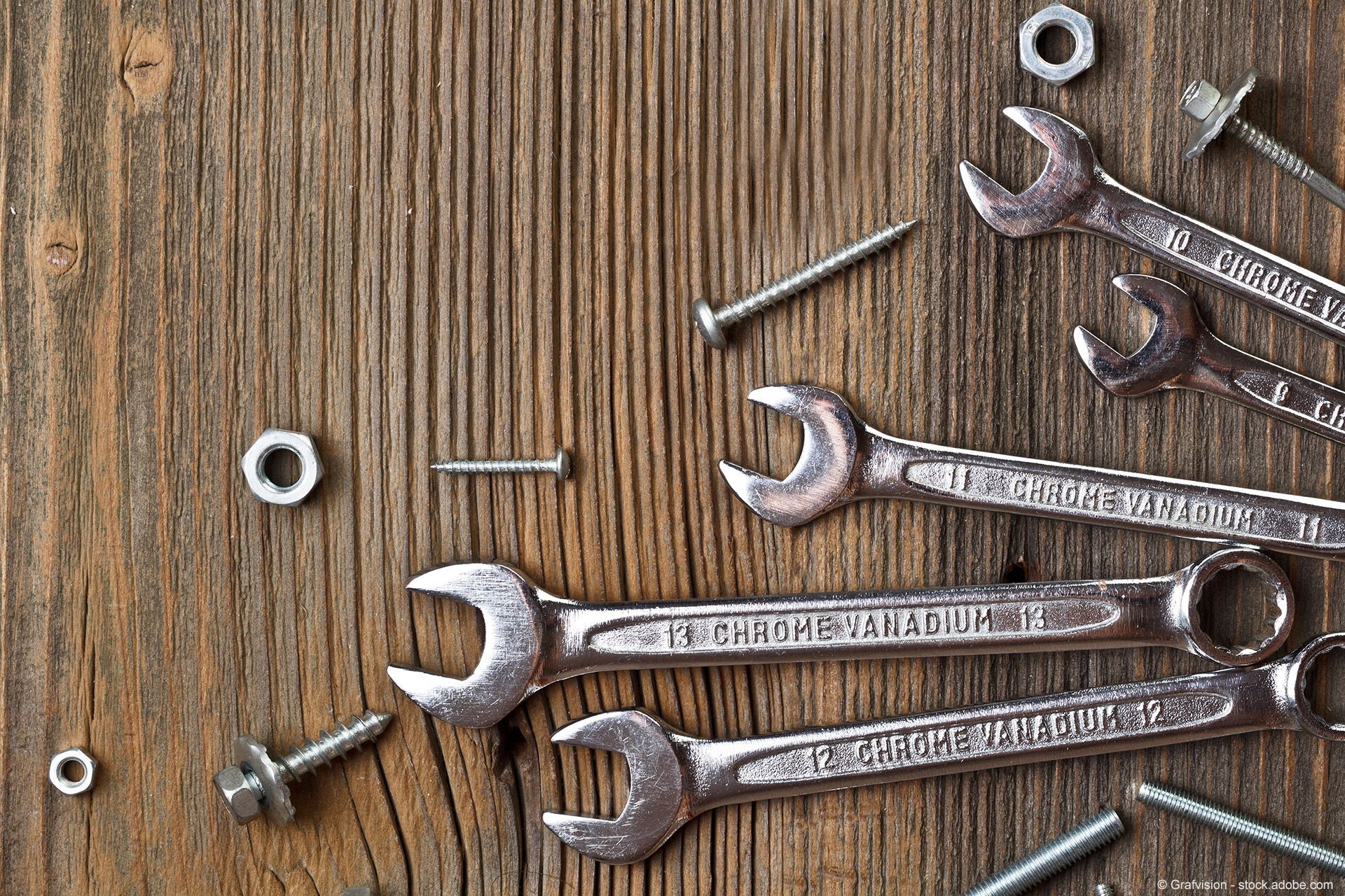 Ein Holztisch mit Schraubenschlüsseln, Muttern und Schrauben darauf