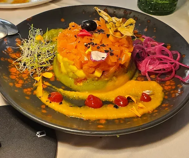 Plato colorido con salmón, aguacate, mango, salsa y guarniciones.