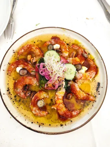 Plato de camarones cocidos en salsa, con guarnición.